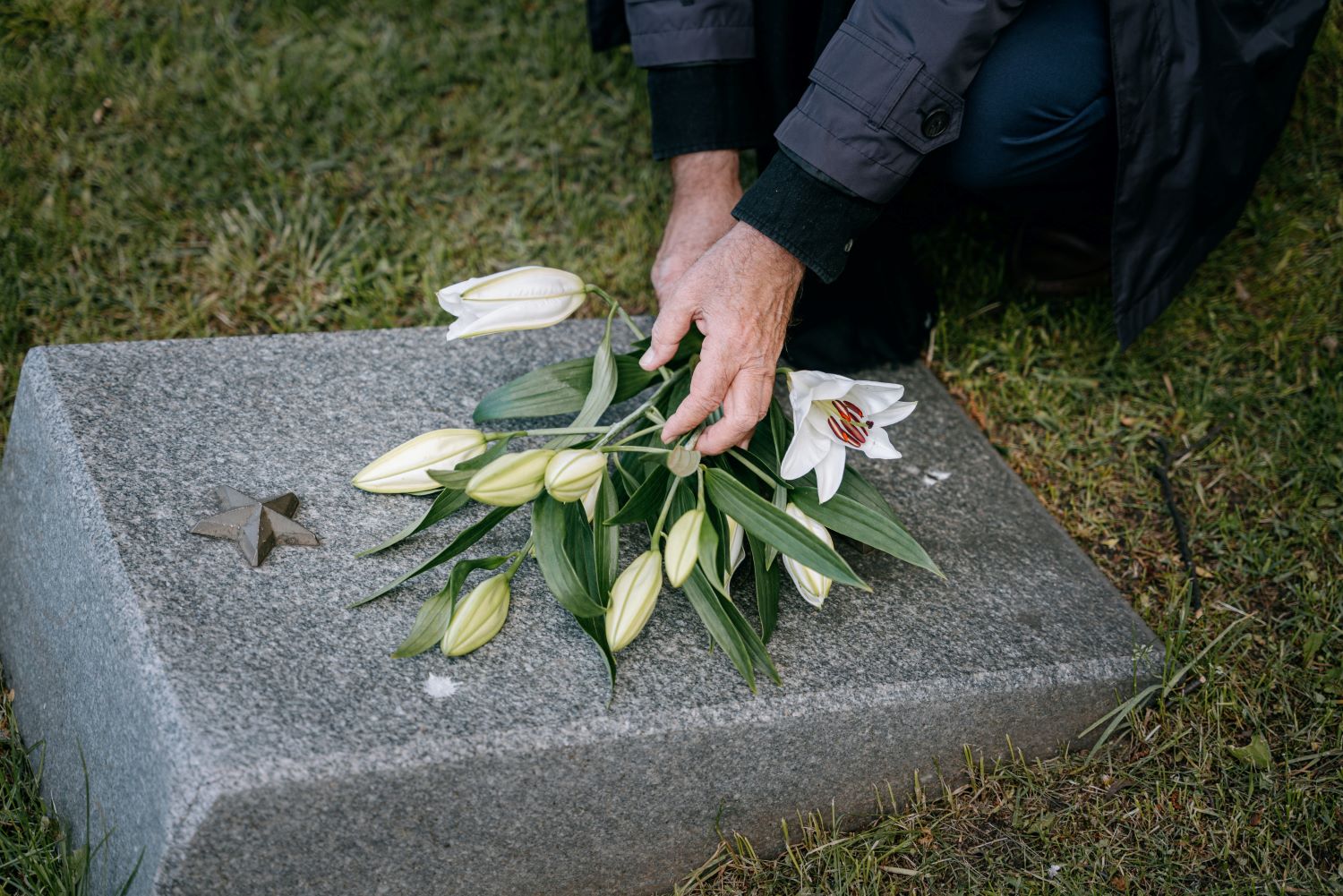 image of a pair of hands laying flowers on a headstone