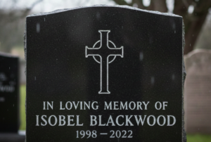 A black tombstone with a carved cross honors Isobel Blackwood, 1998-2022. Rain softly falls, evoking a somber, reflective mood.
